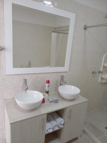 a bathroom with two sinks and a mirror and a shower at Hotel Brisas De Calima in Cali
