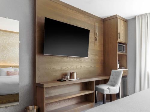 a hotel room with a desk and a television on a wall at voco Niagara Falls - The Cadence by IHG in Niagara Falls