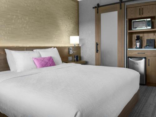 a bedroom with a large white bed with a pink pillow at voco Niagara Falls - The Cadence by IHG in Niagara Falls