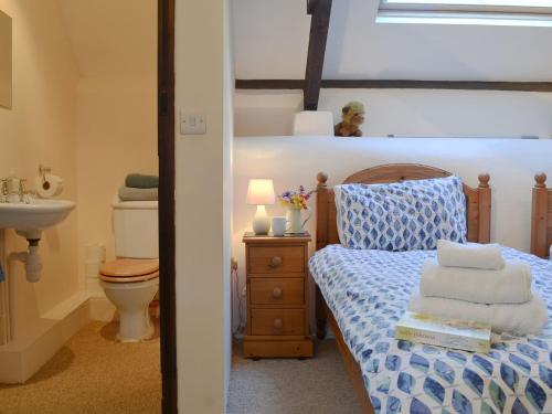 a bedroom with a bed with a sink and a toilet at Clematis Cottage in Holsworthy