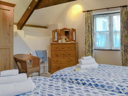 a bedroom with a bed and a dresser and a window at Clematis Cottage in Holsworthy