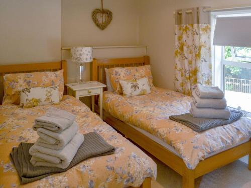 two beds with towels on them in a bedroom at Greenwood Cottage in Longframlington