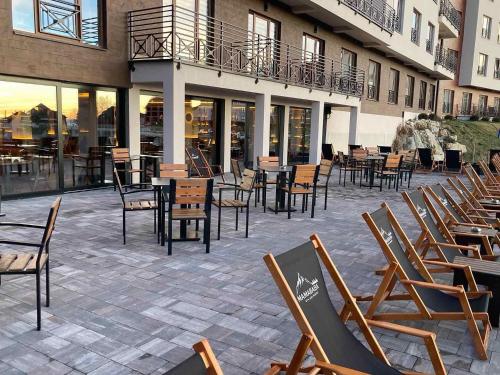 a row of chairs and tables and chairs on a patio at NLux 11 Apartment in Kopaonik