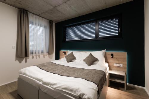 a bedroom with a large bed with a green wall at Aparthotel Na Klenici in Mladá Boleslav
