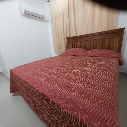 a bedroom with a bed with a red comforter at Binti's Cosy Nest in Dar es Salaam