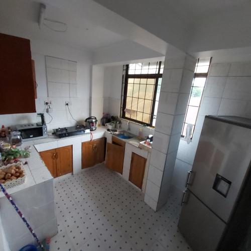 a kitchen with wooden cabinets and a stainless steel refrigerator at Binti's Cosy Nest in Dar es Salaam