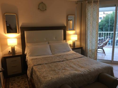 マルベーリャにあるMarbella Apartmentのベッドルーム1室(ランプ2つ付)、バルコニーが備わります。