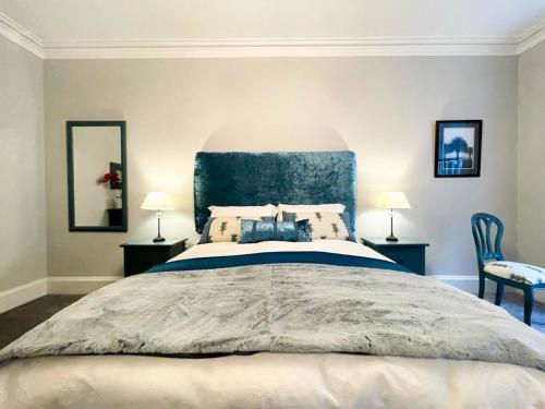 een slaapkamer met een groot bed met een blauw hoofdeinde bij 2Bed, Private Garden & Fireplace, Near Water of Leith in Edinburgh