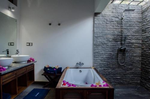 a bathroom with a bath tub and a sink at Home The Residence in Befotaka Bay