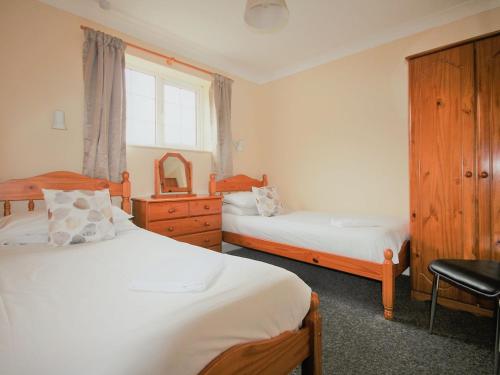 a bedroom with two beds and a dresser and a window at Tom Putt in Ledbury