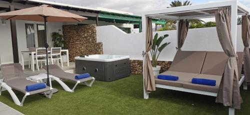a patio with two beds and an umbrella and chairs at VILLAS NEW LANZASUITES PLUS in Playa Blanca