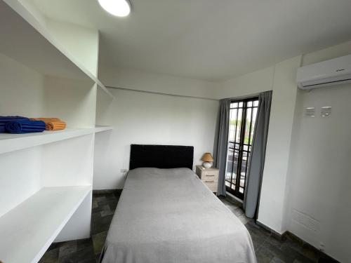 um quarto branco com uma cama e uma janela em Alquiler Temporario Azcuénaga em Morón