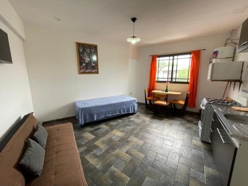 a room with a bed and a kitchen with a table at Alquiler Temporario Azcuénaga in Morón