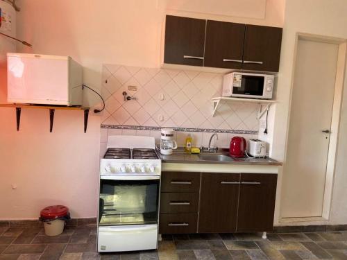 a small kitchen with a stove and a microwave at Alquiler Temporario Azcuénaga in Morón