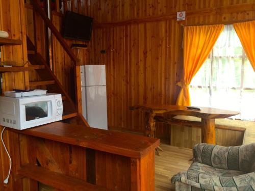 a kitchen with a microwave on a counter and a refrigerator at Refugio de Caty in Bahía Mansa