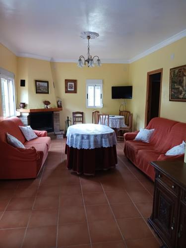 sala de estar con mesa y 2 sofás rojos en Casa Don Julio, en Jimera de Líbar