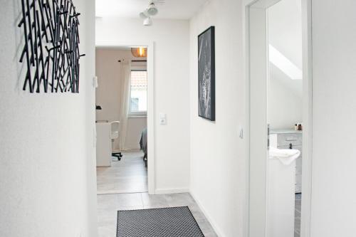 a hallway with white walls and a black and white art on the wall at BlackNCozy - Design Appartement mit Boxspringbett und Balkon in Lörrach