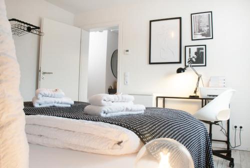 a white bedroom with towels on a bed at BlackNCozy - Design Appartement mit Boxspringbett und Balkon in Lörrach