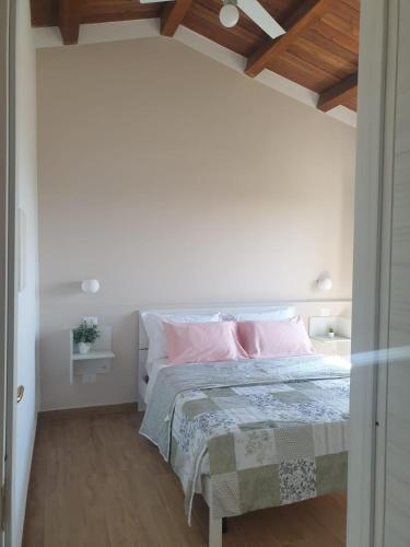 a bedroom with white walls and a bed with pink pillows at AGRI ART in San Benedetto Ullano