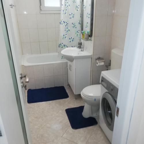 a bathroom with a toilet and a sink and a washing machine at Ruud Mall in Timişoara