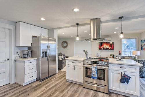a kitchen with white cabinets and stainless steel appliances at Tacoma Dash Point Beach Cabin with Balcony! in Tacoma