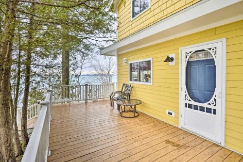 a yellow house with a deck with two chairs on it at Waterfront Cottage on Sawmill Bay with Deck! in Clayton