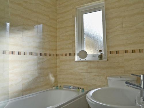 a bathroom with a tub and a toilet and a window at The Meadow Flat in Shanklin