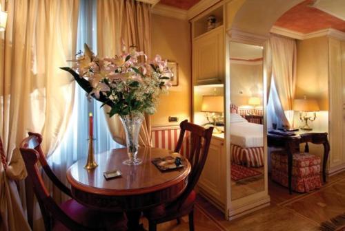 a room with a table with a vase of flowers on it at Petit Palais Hotel De Charme in Milan