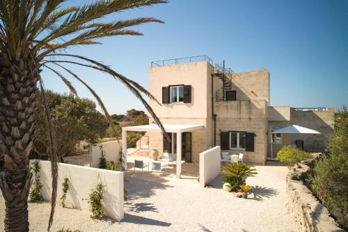 uma casa com uma palmeira em frente em Villa Rocce Bianche em Favignana