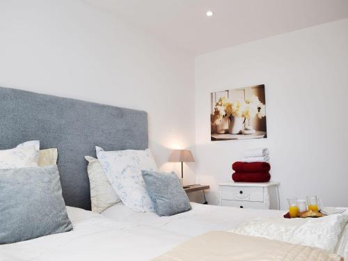 Schlafzimmer mit einem Bett mit weißer Bettwäsche und blauen Kissen in der Unterkunft Bramble Cottage in Leven-Fife