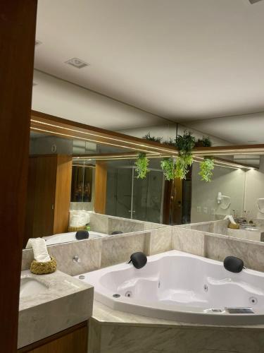a large white tub in a bathroom with mirrors at Île de Pipa com Hidromassagem in Pipa