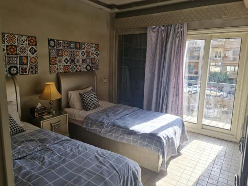1 Schlafzimmer mit 2 Betten und einem Fenster mit Aussicht in der Unterkunft شقق للايجار اليومي المهندسين - الدقي -الزمالك in Kairo
