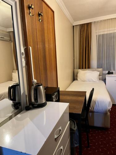 a hotel room with two beds and a kitchen with a desk at Paris Hotel in Istanbul