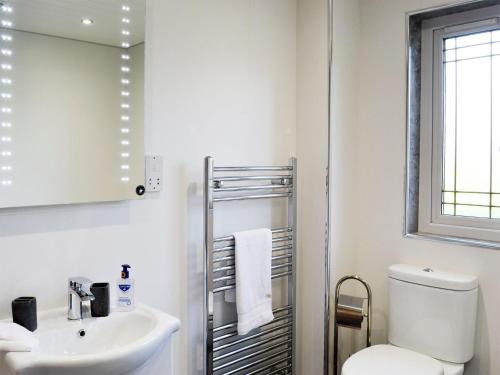 a white bathroom with a toilet and a sink at Hillview in Beith