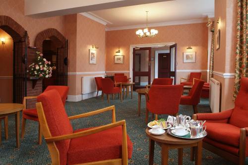 a restaurant with red chairs and tables and chairs at Saxonville Hotel in Whitby