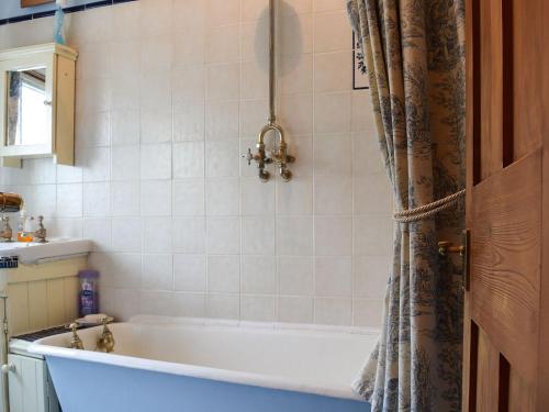 a bathroom with a tub and a shower curtain at Rebeccas Cottage in Ashby Saint Ledgers