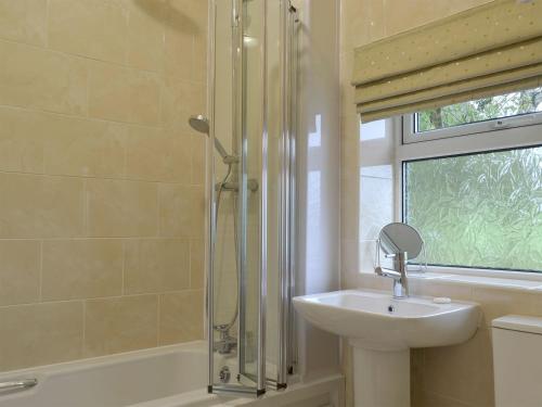 W łazience znajduje się umywalka i prysznic. w obiekcie The Mill Cottage w mieście Ault Hucknall