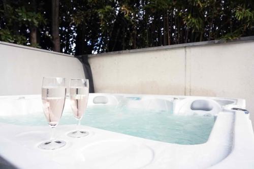 Dois copos de vinho sentados numa mesa ao lado de uma banheira em Chill & Work - Villa spa & piscine à Toulouse em Toulouse