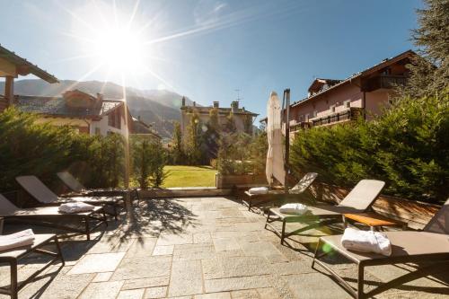 a patio with lounge chairs and the sun shining at Sottovento Luxury Hospitality in Bormio