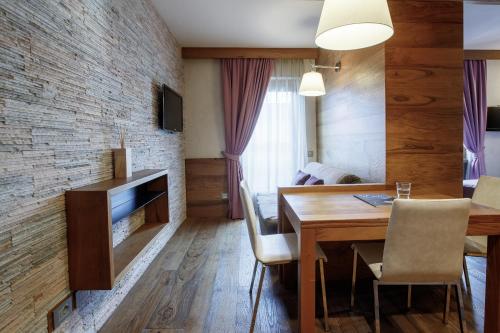 a living room with a dining room table and a brick wall at Sottovento Luxury Hospitality in Bormio