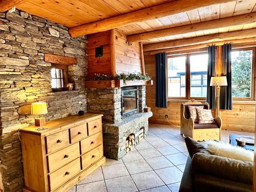 a living room with a stone fireplace in a log cabin at Chalet Les Cocales Résidence Séjour et Nuitées B&B - Appartement Pin Sylvestre in Bessans