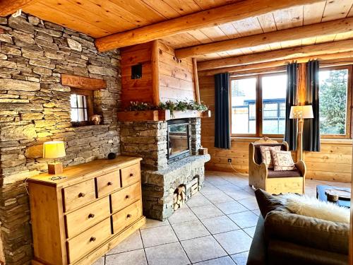 Chalet Les Cocales Résidence Séjour et Nuitées B&B - Appartement Pin Sylvestre في بيسّانس: غرفة معيشة مع موقد حجري في كابينة خشب