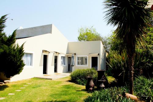 a white house with a palm tree in the yard at La Coscello Guest House in Edenvale