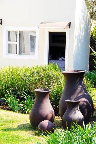 two vases sitting in the grass in front of a house at La Coscello Guest House in Edenvale