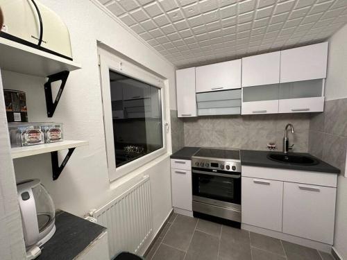 a small kitchen with white cabinets and a sink at Mini Appartement neben Theater in Duisburg