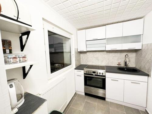 a white kitchen with a sink and a stove at Mini Appartement neben Theater in Duisburg