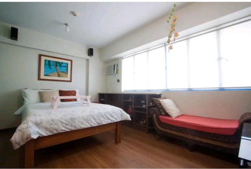 um quarto com uma cama e um banco vermelho em WestParc Cedar Alabang em Manila