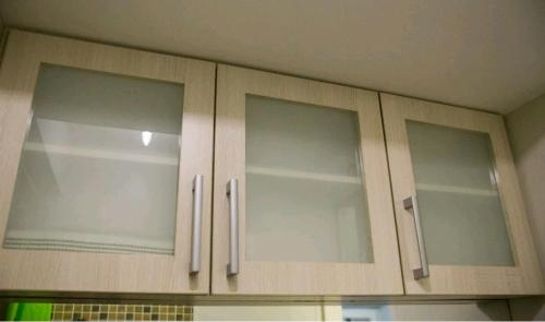 a kitchen with three cabinets with glass doors at WestParc Cedar Alabang in Manila