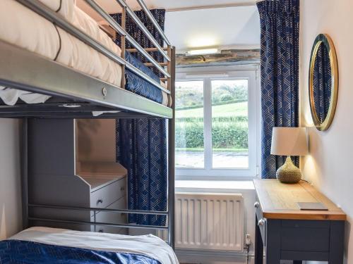 a bedroom with a bunk bed and a desk and a window at Thornton Cottage in Grizebeck