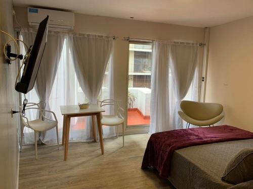 1 dormitorio con 1 cama, mesa y sillas en Rent Scalabrini y Santa Fe en Buenos Aires